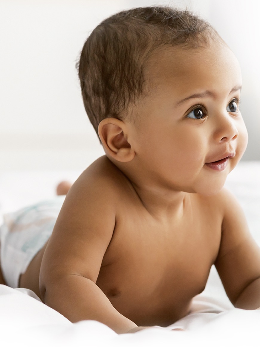 Pampers : un bébé couché sur le ventre, en couche Pampers Harmonie